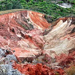 Erosion in Madgascar reveals bright red, orange and cream colored soil beneath what was formerly covered in vegetation.