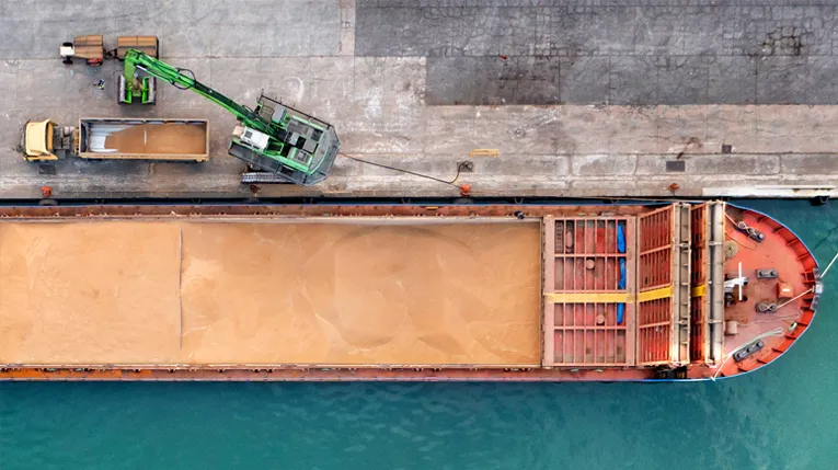 Aerial photo of a large shipping barge next to a concrete pier.